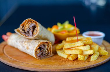 Doner kebab in lavash bread. Close-up delicious chicken doner burrito on black background. Potato chips. selective focus