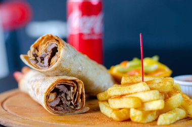 Doner kebab in lavash bread. Close-up delicious chicken doner burrito on black background. Potato chips. selective focus