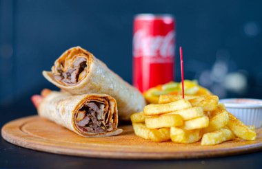 Doner kebab in lavash bread. Close-up delicious chicken doner burrito on black background. Potato chips. selective focus