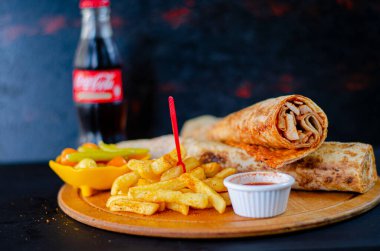 Doner kebab in lavash bread. Close-up delicious chicken doner burrito on black background. Potato chips. selective focus