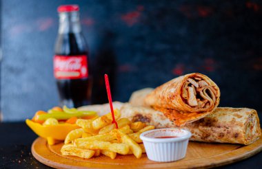 Doner kebab in lavash bread. Close-up delicious chicken doner burrito on black background. Potato chips. selective focus