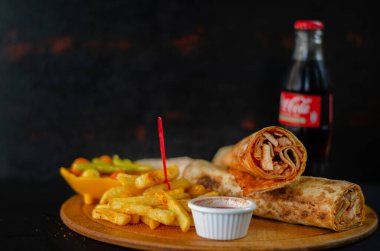 Doner kebab in lavash bread. Close-up delicious chicken doner burrito on black background. Potato chips. selective focus