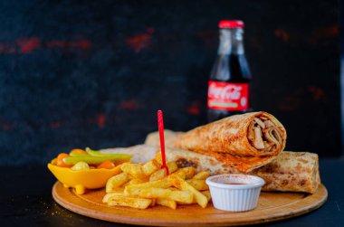 Doner kebab in lavash bread. Close-up delicious chicken doner burrito on black background. Potato chips. selective focus