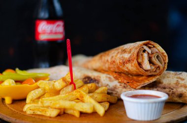 Doner kebab in lavash bread. Close-up delicious chicken doner burrito on black background. Potato chips. selective focus