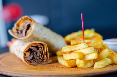 Doner kebab in lavash bread. Close-up delicious chicken doner burrito on black background. Potato chips. selective focus
