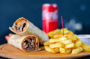 Doner kebab in lavash bread. Close-up delicious chicken doner burrito on black background. Potato chips. selective focus