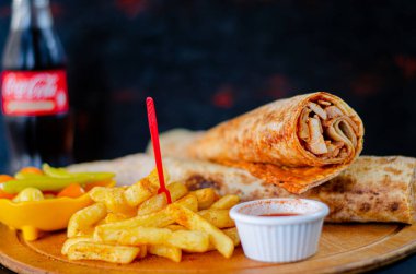 Doner kebab in lavash bread. Close-up delicious chicken doner burrito on black background. Potato chips. selective focus