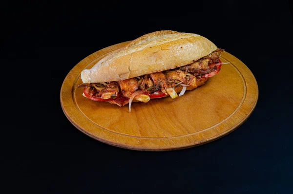 Chicken doner kebab on hamburger bun. Doner kebab in bread on wooden board on black background.