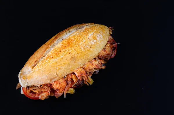 Chicken doner kebab on hamburger bun. Doner kebab in bread on wooden board on black background.