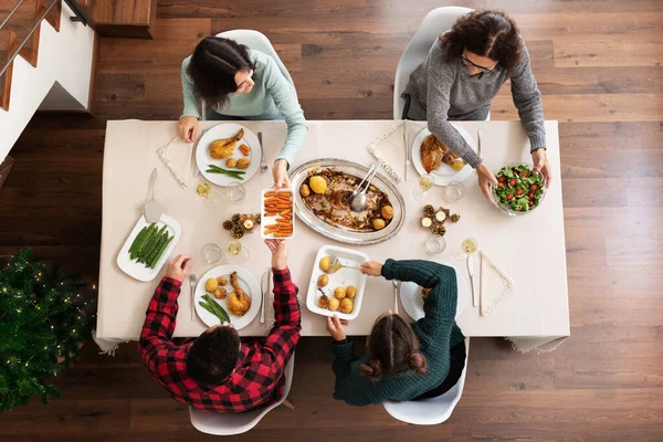 Pohled na šťastnou rodinu, jak spolu slaví vánoční večeři. Předávám talíře. Servíruje jídlo. Požitek. — Stock fotografie