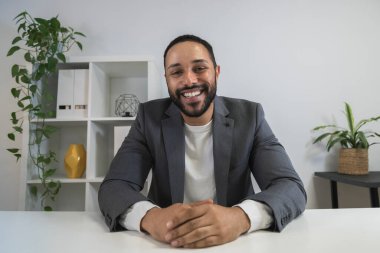 Mutlu ve tatmin olmuş genç Afrikalı Amerikalı girişimci merkez büroda çalışanlarla video görüşmesi yapıyor..