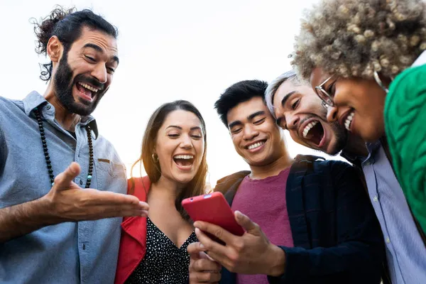 Groep van multiraciale vrienden kijken naar mobiele telefoon met verbaasde expressie. — Stockfoto
