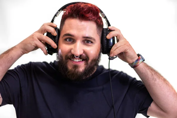Portrett av en ung mann med rødt hår som setter på hodetelefoner mens han ser på kamera. – stockfoto