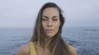 Kumsalda kameraya bakarak gülümseyen beyaz bir kadın. Mutluluk kavramı.