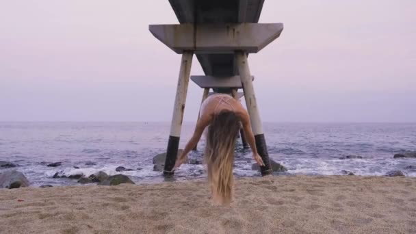 Νεαρή γυναίκα τελειώνει τον χαιρετισμό του ήλιου στην παραλία. Yoga άσκηση κοντά στον ωκεανό. — Αρχείο Βίντεο