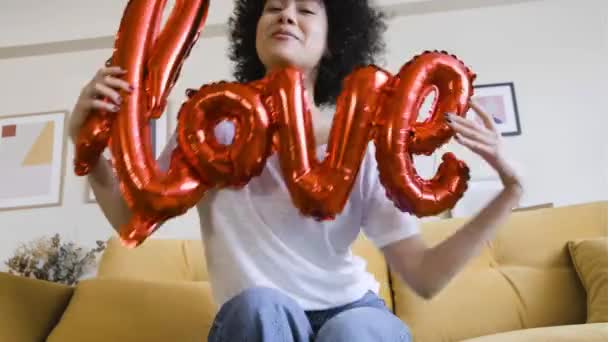 Lange afstand relatie liefde verrassing video call viering. Afro-Amerikaanse vrouw met woord liefde rode ballon — Stockvideo