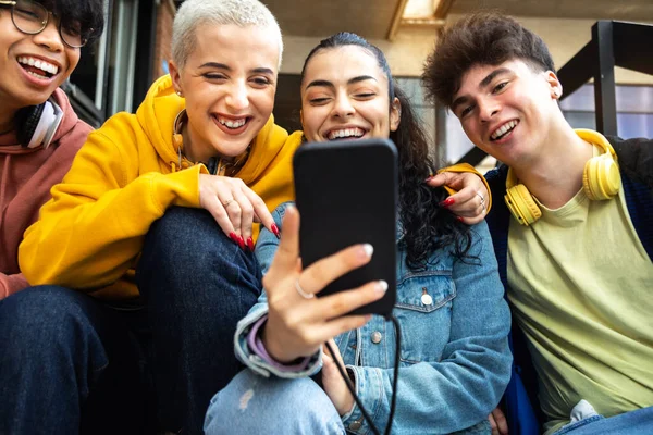 Gelukkige studenten vrienden kijken mobiele telefoon lachen samen. Multiraciale tieners met smartphone buiten. — Stockfoto