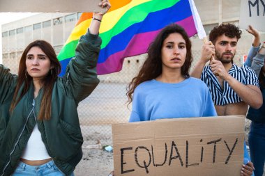 Çok ırklı insanlar, ellerinde karton pankartlar, ellerinde gökkuşağı bayrağı sallayarak LGBT haklarını protesto etmek için birlikte yürüyorlar..