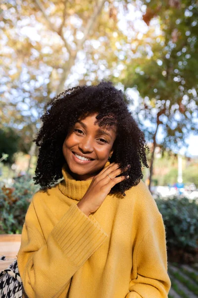 Vertikalt porträtt av leende ung afroamerikansk kvinna tittar på kameran utomhus. — Stockfoto