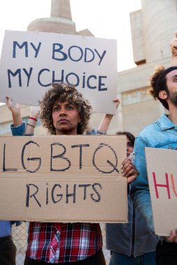 Protesto için elinde LGBTQ karton tabela tutan Afrikalı Amerikalı kadın. Dikey resim.