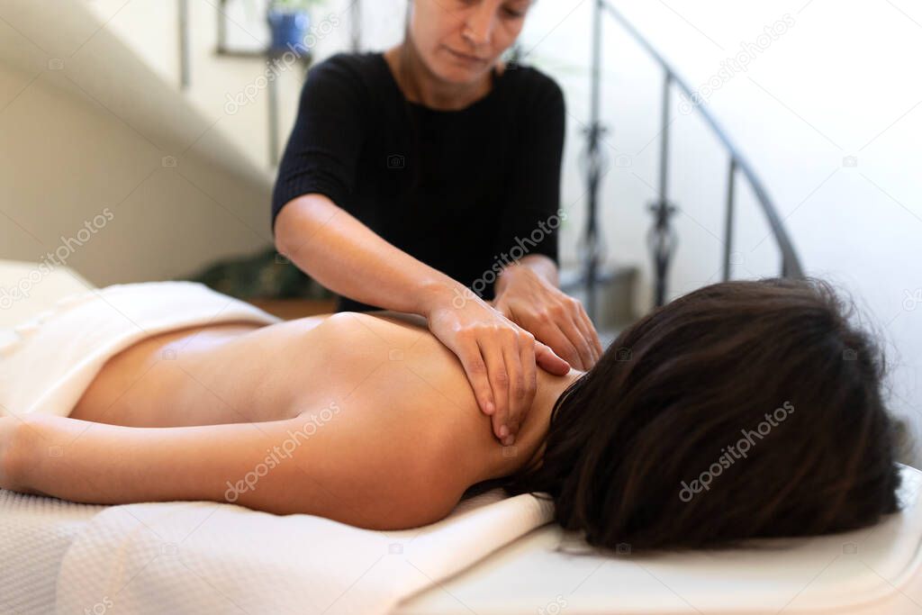 Young caucasian woman receiving therapeutic back massage.