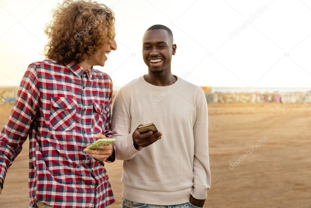 Multiracial male friends enjoy some time together laughing outdoors. Copy space.
