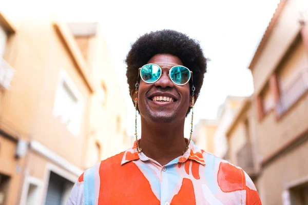 Portret van een jonge, vrolijke en lachende zwarte man die buiten een zonnebril draagt. — Stockfoto