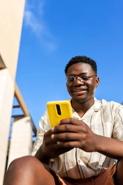 Svart Ung Man Sitter Trappor Utomhus Med Mobiltelefon Vertikal Bild — Stockfoto