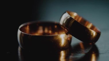 İki altın parıldayan yüzüğe yakın çekim. Evlilik yüzükleri yakın plan. Yüzükler Karanlıkta Parlıyor