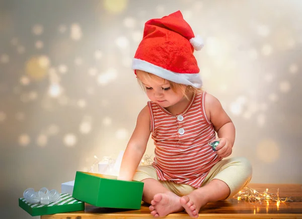 Uma Criança Chapéu Papai Noel Senta Uma Mesa Com Luzes — Fotografia de Stock