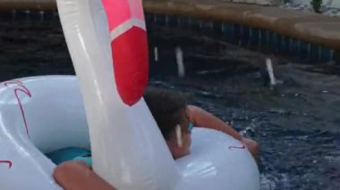 Çocuk kız şişme bir yüzme ringinde yüzüyor.