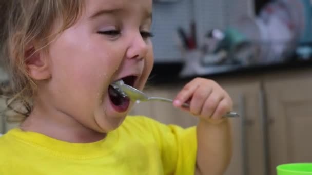 这孩子自己在厨房里拿着勺子吃粥 — 图库视频影像