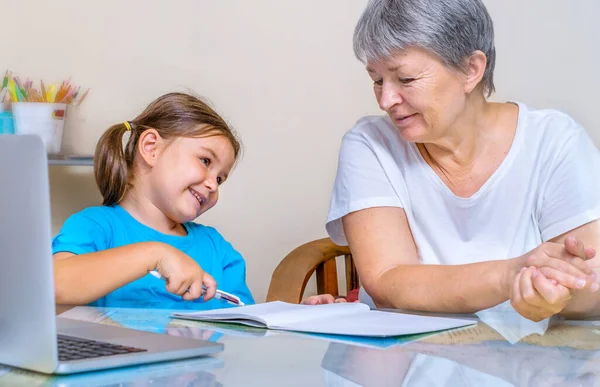 Бабушка Помогает Ребенку Учиться Онлайн Перед Ноутбуком — стоковое фото