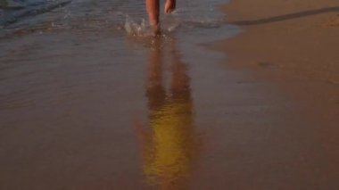 Mutlu çocuk tatilde sahilde suda koşuyor.