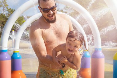 Baba ve çocuk tatilde havuzda su sıçratıyorlar.