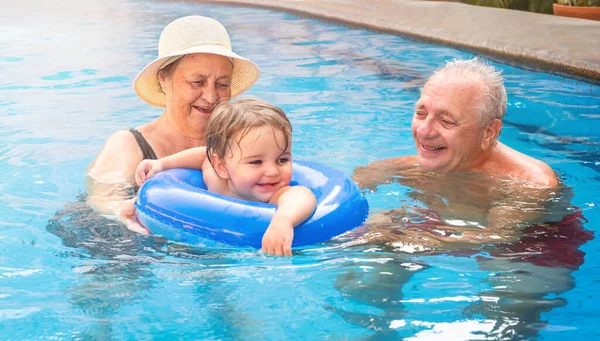 Birkaç yaşlıyla bir çocuk havuzda şişirilebilir bir çemberde yüzüyor.