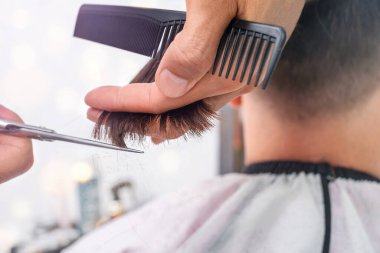 Berber dükkanında saçın uçlarını makasla buduyorum.