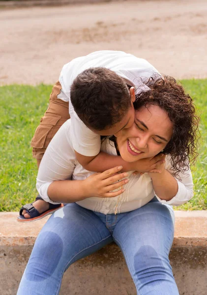 Latin anne ve çocuk güzel bir yaz öğleden sonrasında parkta oynuyorlar. Yaşam tarzı. Oğlum oyunda annesine sevgiyle sarılıyor..