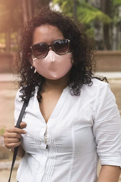 Pembe maske takan genç Latin kadının portresi virüslerin yayılması, grip hastalıkları, halka açık alanlarda grip gibi şeylere karşı koruma sağlıyor..