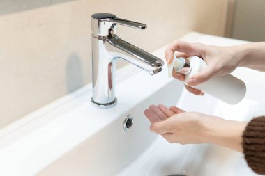 Orta boy, evde ellerini yıkamak için sabun kullanan bir kadın. El hijyeni kavramına yakın çekim. Enfeksiyon ve virüslere karşı koruma.