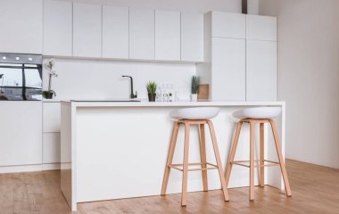 Minimalistic light interior of modern kitchen with island and high chairs