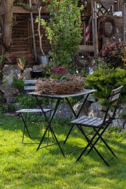  A flower red Saxifraga  arrangement in a basket is set in the garden on a table in a nest