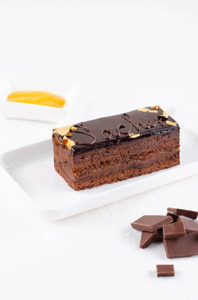 Pastel de chocolate Sacher en plato blanco con chocolate negro y mermelada de albaricoque —  Fotos de Stock