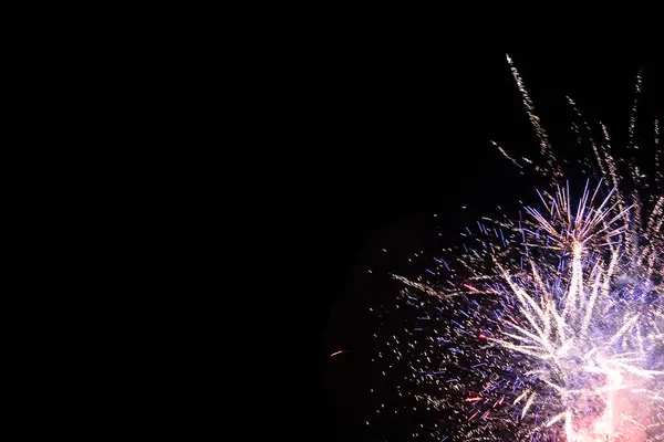 Bir sürü havai fişek kıvılcımı gece karanlığına karşı parlak izler oluşturur.