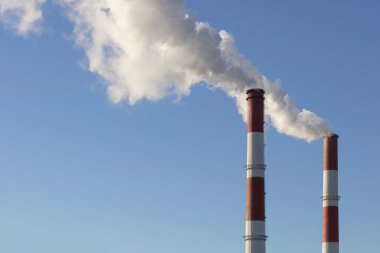 Mavi gökyüzüne karşı güç santralinin iki duman sıvısını izleyin.