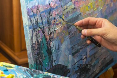 Paletli bir sanatçı palet bıçağıyla resim yapar.