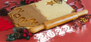 Kırmızı zemin üzerinde ahşap bir tahtada ev yapımı zencefilli kurabiye yapmak için Hamur. Noel ve Yeni Yıl 2022 konsepti. Seçici odak