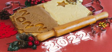 Kırmızı zemin üzerinde ahşap bir tahtada ev yapımı zencefilli kurabiye yapmak için Hamur. Noel ve Yeni Yıl 2022 konsepti. Seçici odak