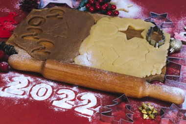 Kırmızı zemin üzerinde ahşap bir tahtada ev yapımı zencefilli kurabiye yapmak için Hamur. Noel ve Yeni Yıl 2022 konsepti. Seçici odak