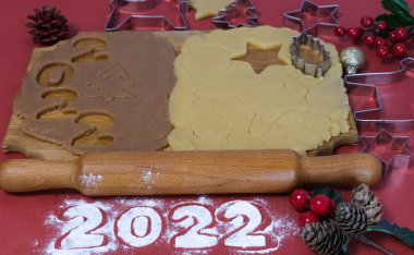 Kırmızı zemin üzerinde ahşap bir tahtada ev yapımı zencefilli kurabiye yapmak için Hamur. Noel ve Yeni Yıl 2022 konsepti. Seçici odak